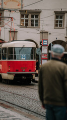Naklejka na ściany i meble An old man looking at a red tram at Prague