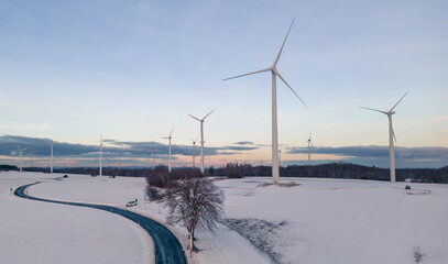 aerial view of wind turbines on the snow covered field at sunset