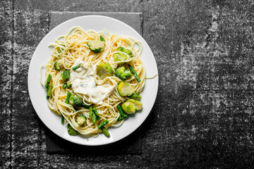 Pasta with vegetables and sauce on a plate.