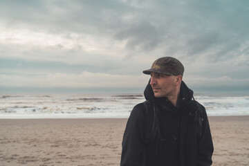 Mann am Strand mit dem R&uuml;cken zum Meer schaut sich um