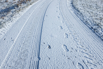 Verschneiter Feldweg mit Reifenspuren und Fußspuren zwischen  Acker und Feld © lebaer