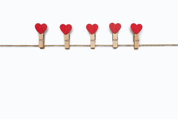 Clothespins decorated with hearts hang on a rope on a white isolated background. Concept for lovers. Valentine's Day holiday. Decor in the form of clothespins and free space for text