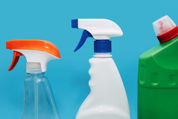 Various spray bottles with detergent on a blue background. The concept of cleaning and disinfection...