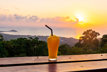 Mango smoothie on the background of beautiful sunset and sea from the view point in Koh Samui Island, Thailand