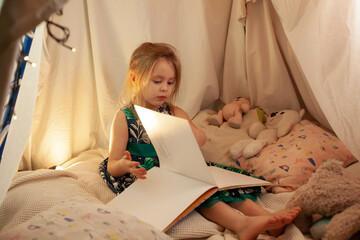 the girl is playing and reading a book in the hut