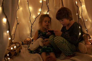 children sit in the hall and look at the tablet