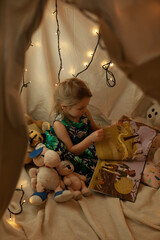 the girl is playing and reading a book in the hut