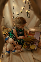 the girl is playing and reading a book in the hut