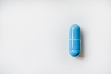One blue capsule with medicine on a white background. The blue pill. Capsule close-up.