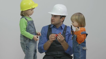 Father with safety construction helmet and two children , family education