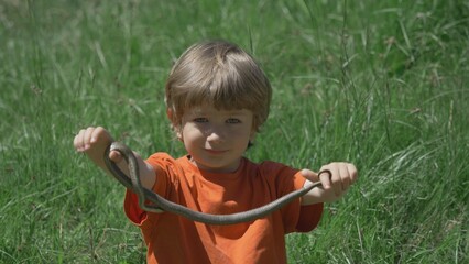 Two little children play with dangerous wild animal, captured snake in nature
