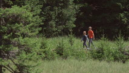 Two children walk on bridge in green nature, brother together explore nature