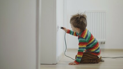 Little kid insert the plug into the socket, risk of electric shock - obrazy, fototapety, plakaty