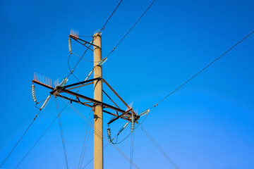 Overhead power line support on the blue sky background.