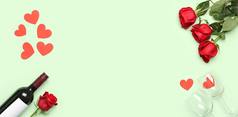 Bottle of wine, rose flowers, paper hearts and glasses on green background with space for text. Valentine's Day celebration