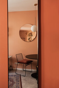 Elegant stylish chair, table, mirror, carpet, colourful coral walls. Modern aesthetic minimalist home living room interior design. Luxury apartment interior