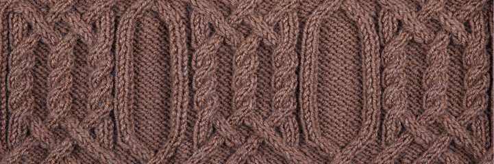Knitted brown background banner. Large knitted fabric with a pattern. Close-up of a knitted blanket. Copy space.