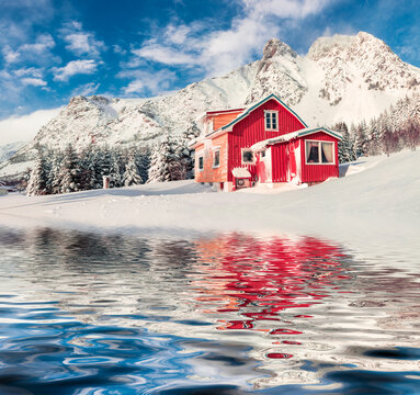Red wooden houses reflected in the calm waters of Norwegian sea. Bright winter view of Vestvagoy island, Norway, Europe. Beautiful morning scene of Lofoten Islands. Traveling concept background.