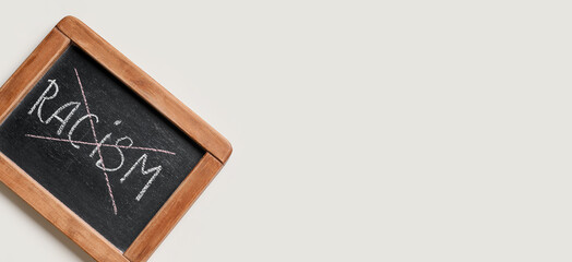 Chalkboard with crossed out word RACISM on white background with space for text