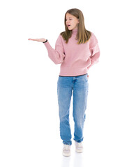 Cute female presenting and showing copy space for product of text and looking on it. Adorable fourteen year old girl in pink sweater and blue jeans posing in studio..