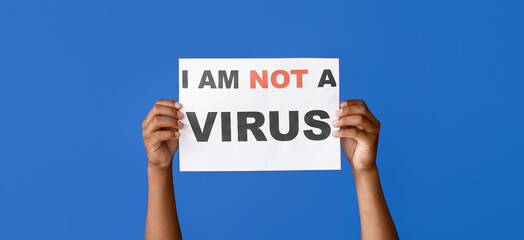 Hands of African-American man with poster on blue background. Stop racism