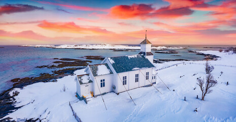Wonderful suswt on Lofoten Islands. Picturesque winter view of Gimsoy Church, Norway, Europe.  Picturesque morning seascape of Norwegian sea. Life over polar circle.