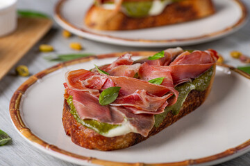 Desayuno de tostada con jamón serrano, pistacho y crema de queso feta. 