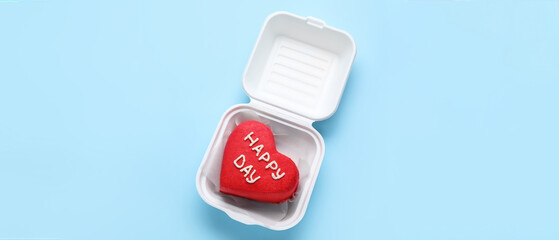 Plastic lunch box with tasty bento cake on blue background. Valentine's Day celebration