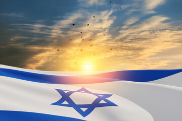 Israel flag with a star of David over cloudy sky background with flying birds on sunset. Patriotic...