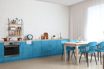 Light interior of modern kitchen with blue counters and dining table