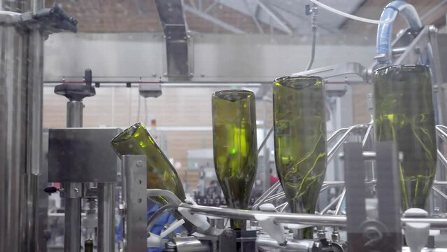 Conveyor with green bottles for bottling wine through glass works