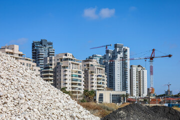 Unfinished buildings and construction cranes on sunny day