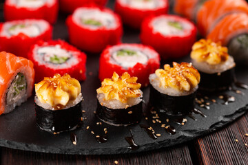 Large sushi set from top on black background close-up. An assortment of various maki nigiri and rolls seafood soy sauce