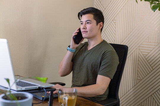 Transgender man working talking on his phone. 