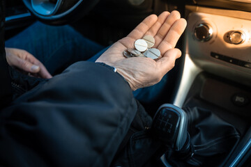 Person counts money, cash, coins sit in the car. Concept of expensive gas, high cost of living....