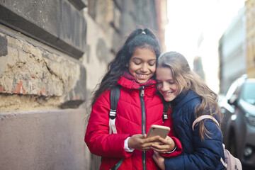 two little girls use a smartphone on the street