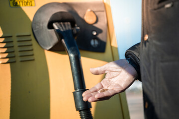 Close up of hand inserting coin into yellow slot machine in a car wash. Self service machine