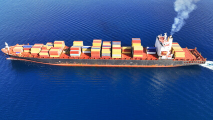 Aerial drone top down photo of huge container ship full of colourful containers cruising deep blue...