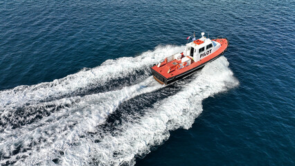 Fototapeta premium Aerial drone photo of red pilot boat cruising in high speed in Mediterranean deep blue sea offering navigational aid to ships