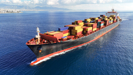 Aerial drone top down photo of huge container ship full of colourful containers cruising deep blue...