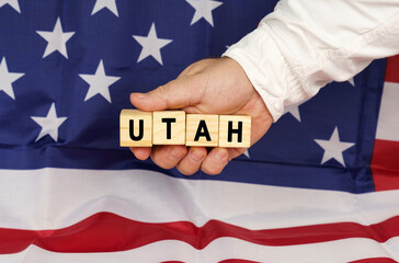 Against the background of the USA flag, a man's hand with cubes with the text - UTAH