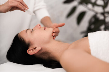 Obraz na płótnie Canvas Crop unrecognizable beautician doing face massage with gua sha to client