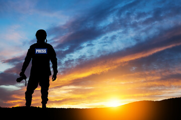 Photojournalist silhouette documenting war or conflict. Photojournalist at sunset. War, army,...