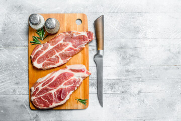 Raw pork steaks on cutting Board.