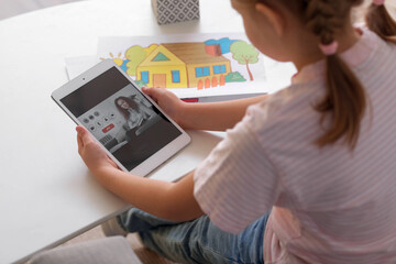 Little girl video chatting with psychologist on tablet computer at home, closeup