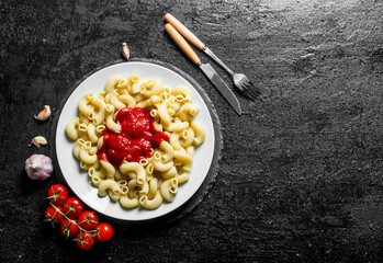 Pasta with tomato sauce on a plate and fresh tomatoes.