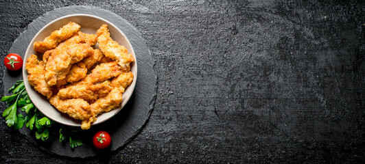 Chicken strips in a bowl with parsley and tomatoes.