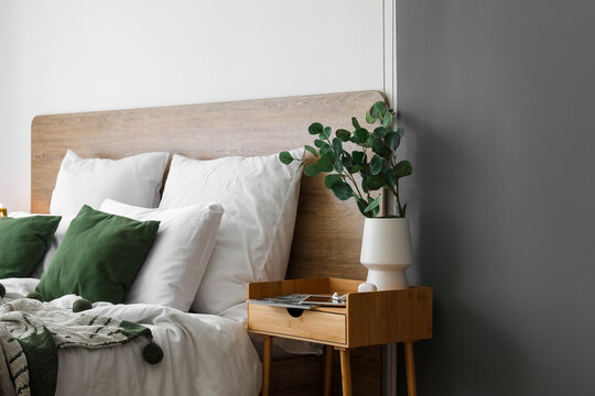 Vase With Eucalyptus, Devices And Magazine On Wooden Table In Bedroom