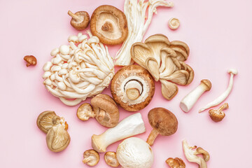 Heap of different fresh mushrooms on pink background