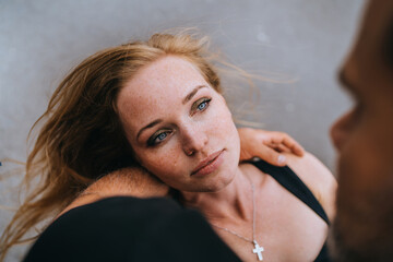 Fototapeta premium Young redhead American young adult woman looks at her man. Close up of man holding girlfriend on hand wants to kiss. Romance. Cropped image of lovers, couple in love. Valentine's day. Relations.